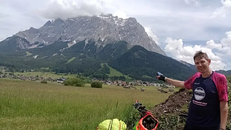Christian Waniaus beim Alpencross, er deutet mit dem Finger auf einen großen Berg hinter sich Christian Waniaus beim Alpencross, er deutet mit dem Finger auf einen großen Berg hinter sich